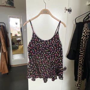 Linne med blommor - Linne köpt på ASOS. Svart med färgglada blommor och kjol längst ner. Fint skick, använd fåtal gånger. Samfraktar gärna! ❤️