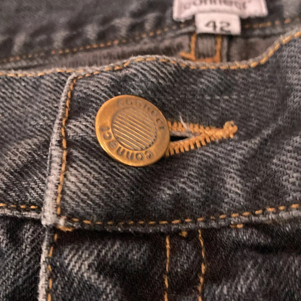Grå blå jeans med säkerhets nålar i ena bakfickan. Farkut & Housut.