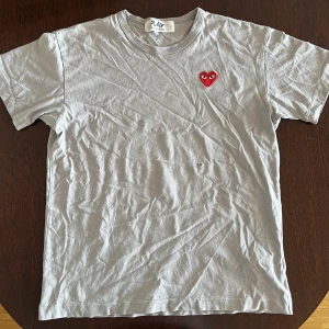 Cdg Play Grå T-shirt  - Notera defekt på bild 3! Strlk XL men liten passform. Äkta såklart. Pm vid frågor. Allt gott! 
