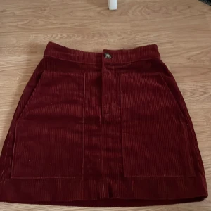 Manchester kjol - Manchester kjol i mörkröd. Högmidjad. Stora fickor 