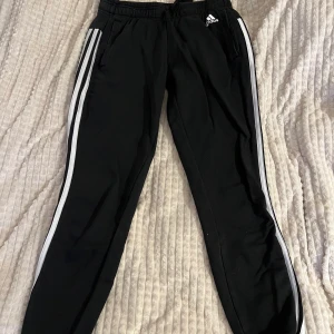 Adidasbyxa - Svarta adidas med vita ränder på sidan av varsitt ben, lågmidjade med snörning i midjan