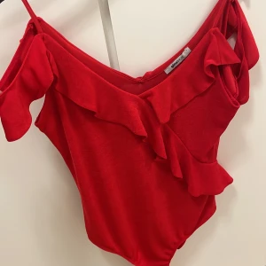 Röd body från Gina tricot - Jätte söt röd body från Gina tricot. Off shoulder med volanger och tight och figurnära.