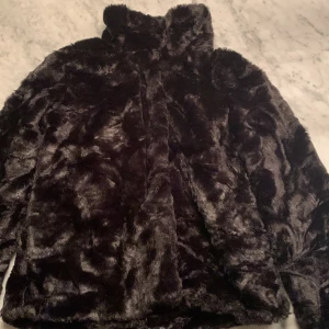 Lindex storlek 140  - En svart pälsjacka med hög krage. 