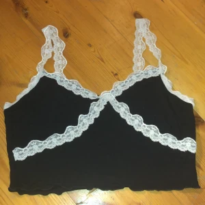 Svart Topp med Vit Spets - Väldigt mjukt och bekväm topp. Använd några gånger men i helt nyskick annars. Lite stretchig, passar bra L-1XL.