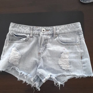 Jeans shorts - Low waist Jeans shorts från Guess med pärlor i grön,gul och röda färger.Hål men med tyg under. Köpta 4 år sedan i Usa men i bra skick.(runt midja 66 cm och längd 24 cm)❤