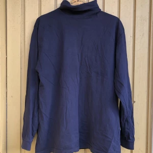 Mörkblå polotröja - Mörkblå långärmad polotröja i rejält tyg.  Skick: Mycket bra skick, inga tecken på användning 