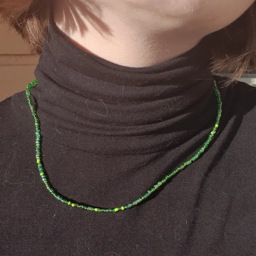 Halsband gjort med gröna glas och plast pärlor med klämma i metall.. Accessoarer.