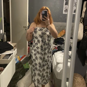 Vit klänning  - Vit klänning med palmer på från Thailand. Står ingen storlek men gissar på XS/S då den är alldeles för tajt för mig som är M. Använd 3 gånger.