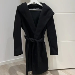 Zara kappa - Svart zara kappa med bälte i midjan , samt med en stor luva. 