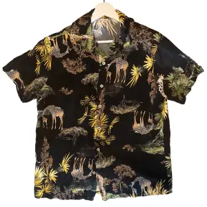 An black short sleeved summer shirt with a sleek savanna print. 