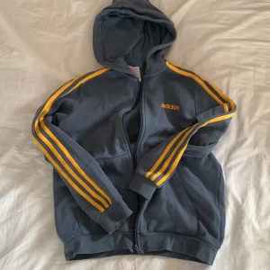 Adidaströja - Blå ziptröja från Adidas med gula ränder. Storlek 12 år men passar mig bra som är S⭐️ Först till kvarn‼️‼️‼️‼️‼️ANVÄND INTE KÖP NU