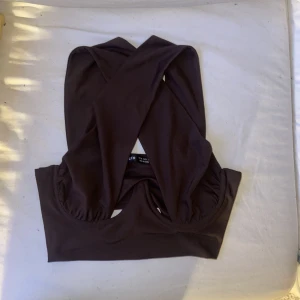 Topp 🤎 - Brun topp med byglar under brösten och axelband som korsas framtill. Superfin i lite festligare sammanhang. 