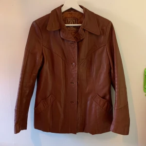 Skinnjacka - Röd/brun mellan lång skinnjacka. Det står storlek 42 men är lite mindre i storleken, sitter lagom oversized på mig som är S. 