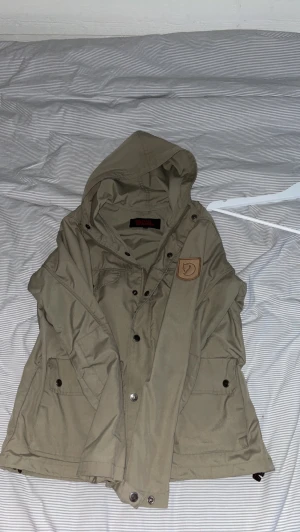 fjällräven jacka  - Mörk/oliv grön fjällräven jacka( vind jacka) storlek: XS, inga hål eller märken! perfekt nu när våren är påväg och sen perfekt till sommaren! Hade självt använt ifall jag hade rätt storlek! Skriv vid intresse( ny pris: 3000