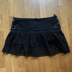 Mini kjol  - Minikjol, svart nät (transparent)  Detaljer i metall och dragkedja baktill. Lite stretch kring midja