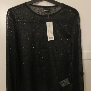 Skimmrig topp - En skimmrig topp med glitter likande paljetter, perfekt för en utekväll. Aldrig använd med prislappen kvar.