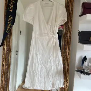 En vit klänning med V ringning och omlott (endast använd en gång!)
