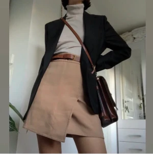 Beige kjol - Beige kort kjol med omlott/slits. Tyget är ganska tjockt så den är perfekt till höst/vinter/tidig vår. Så snygg med en kavaj! Sparsamt använd. Passar bäst en XS-S. Skärpet ingår ej. Skriv för fler bilder eller om du har frågor 💓