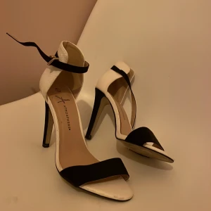 Fina höga öppna skor i nyskick  - Bara använda någon enstaka gång! Svartvita Atmosphere skor. Höga stilettklackar, öppna med spänne upptill. Säljer de för 89+frakt 49kr(står köparen för)