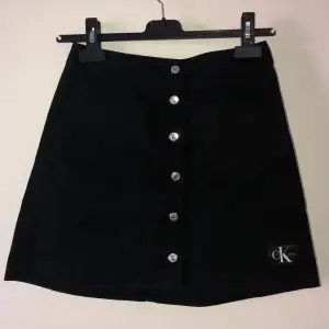 jättetsöt svart kjol med knappar&fickor från Calvin Klein i nyskick! köptes för nåt år sedan men aldrig blivit använd då den inte riktigt är min stil. endast testad. 