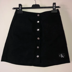 Calvin Klein kjol - jättetsöt svart kjol med knappar&fickor från Calvin Klein i nyskick! köptes för nåt år sedan men aldrig blivit använd då den inte riktigt är min stil. endast testad. 