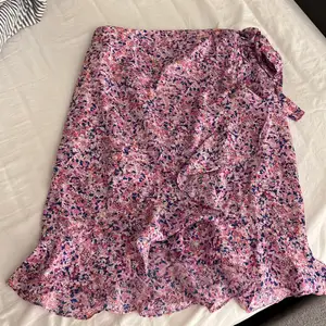En lila rosa blommig kjol med blåa detaljer. Köpt förra sommaren nyskick. Säljs pågrund av knappt nån andvändning.  