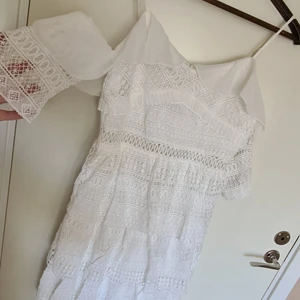 Söt klänning strl M - Perfekt för studenten! Söt vit klänning.  Ny och helt oanvänd från märket Dennis Maglic. Faller väldigt fint och klänningen har ett lyxigt tyg/virkningar. Dragkedja baktill och axelbanden går att justera. Otroligt fin på men alla volanger och detaljer.