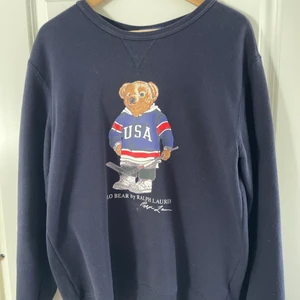 Polo Ralph Lauren tröja - Polo Ralph Lauren tröja med USA hockey björnen som tryck. Mindra fläckar som enkelt går bort med lite vatten. Modellen är stor i kragen så den är schysst som overshirt liknande. Barn XL men passar mig som är 17 år och 186cm lång.