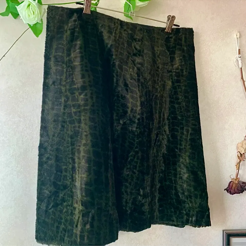 Pälsimitation kjol med ormmönster i mörkgrön och svart, den är i rak modell med mjukt tyg. I vissa ljus ser den svart ut och sen ser man att det är ormmönstrad i grönt 🐍. Kjolar.