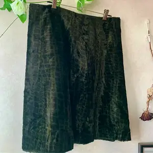 Pälsimitation kjol med ormmönster i mörkgrön och svart, den är i rak modell med mjukt tyg. I vissa ljus ser den svart ut och sen ser man att det är ormmönstrad i grönt 🐍