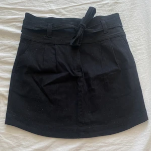 Shinestar Svart Jeanskjol stl. M - Svart jeanskjol från Shinestar med dragkedja/knappar och band för snyte i samma material. Endast provat, lappen sitter kvar