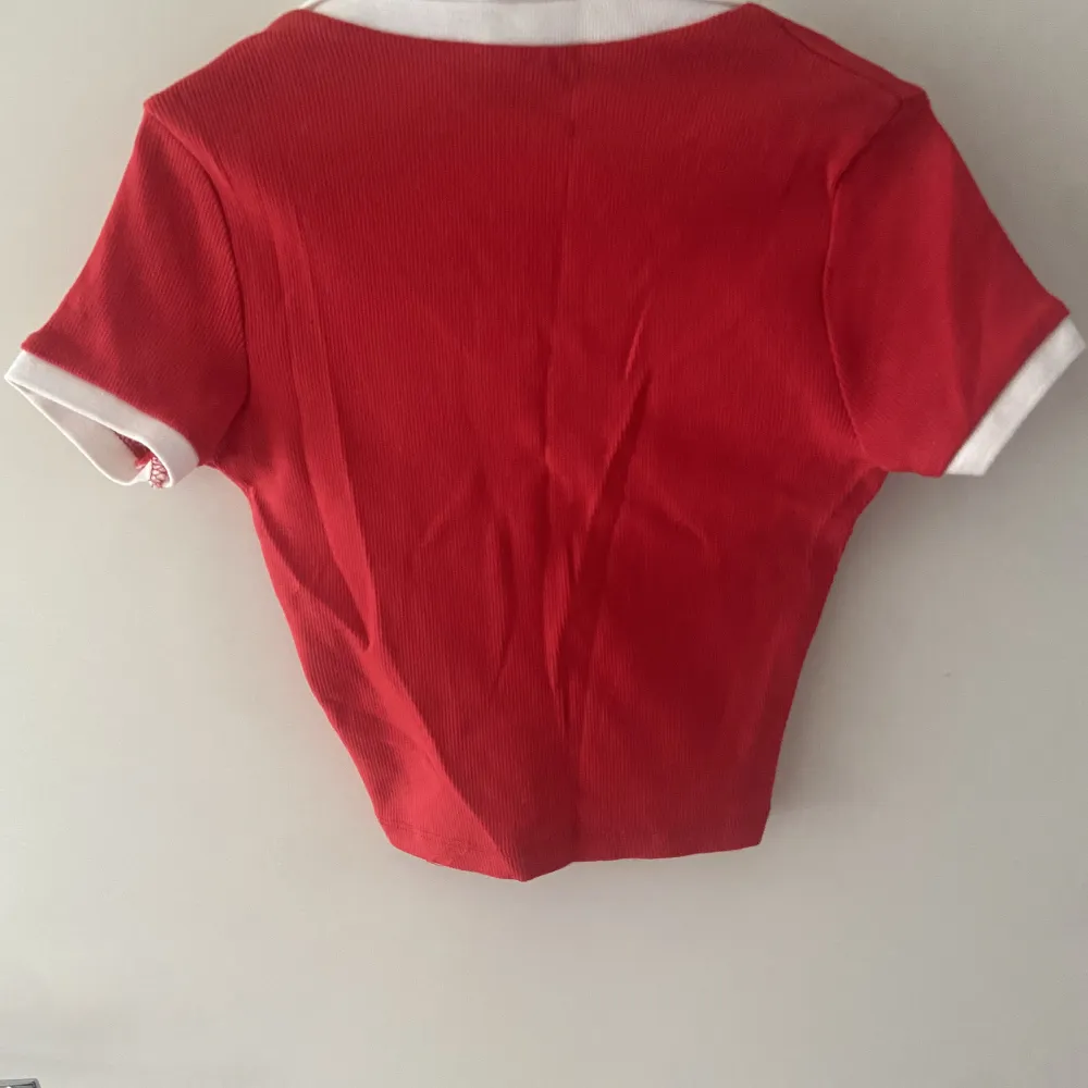 Croppad röd tshirt med vikbar krage. Fin urringning så halsband syns. Köpare står för frakten. T-shirts.