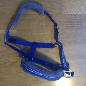 Grimma  - Säljer min grimma då den inte längre används. Använd ett par ggr. Stolek: Ponny Färg: Blå med grå fluff. 100 kr