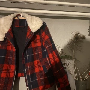 RutJacka  - Blå/röd rutig jacka med vit pälskrage. Lätt fodrad och perfekt för vädret ute nu! I mycket fint skick!