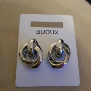 Silverfärgade örhängen  - Silverfärgade örhängen med ringar, cirka 1,5cm i diameter i den stora ringen. ALDRIG ANVÄNDA!