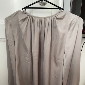 Sidenblus - En beige/grå siden blus. Så himla fin på men har aldrig kommit till användning då jag inte tycker färgen passar på mig. Bra skick!