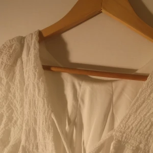 vit klänning - Jag säljer min konfirmationsklänning som endast är använd en gång och nu inte kommer till användning. Något kort på mig som är 1,71. Perfekt till konfirmation eller student! Klänningen är öppen i ryggen och har knytdetalj framtill. Köparen står för frakt!