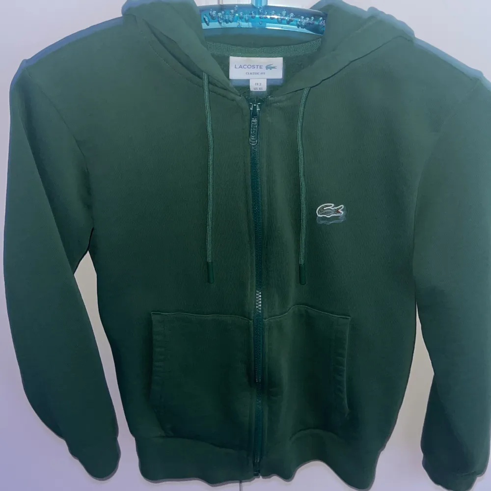 Lacoste hoodie, använd cirka 2 gånger. Grön. Storlek XS, passar 160-170 cm lång. Nypris är cirka 1600 kr, men jag säljer den för 850 kr.. Hoodies.
