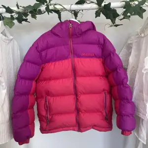 En färgglad puffer jacket från marmot, med luva