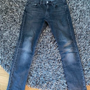 Gråa levis 502 jeans 29/32 - Ett par levis jeans som är relativt mycket använda men som fortfarande är i bra form och de har inga märken på sig eller något liknande. Snygga gråa byxor med lite svarta detaljer. Säljer dessa då jag inte längre kan ha dem. Ordinarie pris 1099kr