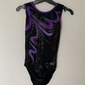 Svart gymnastikdräkt med lila detaljer  - Fin svart gymnastikdräkt dräkt med lila detaljer. Säljes för 100kr är rätt använd men inga hål eller skador, men glittret börjar tona.