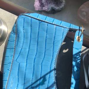 Säljer en söt blå väska!  Väskan är i mörkblå färg med ett glansigt matrial. Säljs pågrund av att jag har för mycket väskor. Köparen står för frakten  (Första bilden visar bäst ljus) 