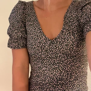 Söt klänning - Supersöt klänning med små rosa blommor. Fina detaljer kring bröstet och axlar/armar. Fin passform.  Från H&M Svart med vita och rosa detaljer/blommor. Använd fåtal gånger. Jättefint skick. Inga skador eller fläckar.  Storlek 34. 🖤💗🤍🖤💗🤍