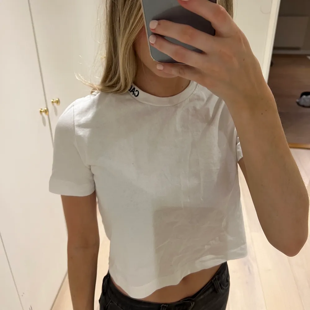 Kortare t-shirt från Calvin Klein med coolt logo tryck vid halva halsen i storlek XS🤍. T-shirts.