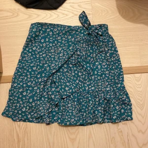 Kjol - Säljer denna supersöt omlottkjolen i blommigt mönster! Inte använd en ända gång!!! Den är lite mer åt det gröna hållet än vad som syns på bilderna 😋