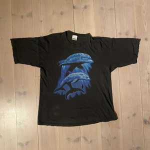 Vintage T-shirt 80 tal - En väldigt cool och urtvättad T-shirt med ett par år på nacken. Antagligen från 80/90 tal med tanke på slitagen. Den är sliten har blandannat ett lite större hål på framsidan som kan sys igen och annars lite små hål som är svåra att se men med tanke på åldern är den bra skick. Storleken är bortsuddad men skulle säga att den sitter som en boxy L!