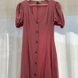 Rosa klänning  - Rosa klänning från H&M med knappar och puffärmar. 