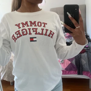 Tommy Hilfiger strl 164 - Vit långärmad Tommy hilfiger tröja med tryck på. Jätte fin och mjuk passar mycket bra för personer med strl XS/S och köpt från kids brand store för några år sen men inte använt mycket. Inte så tjockt material. Köpt för ca 250kr. Pris kan diskuteras💞