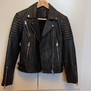 Äkta skinnjacka från Allsaints - Svart skinnjacka från Allsaints, använd max 2 gånger då den är för liten för mig. Något kort i ärmarna vilket gör att den passar bäst för en kortare person. US size 4 (EU 36) men liten i strl.Kan mötas upp i SthlmUppsala annars står köparen för frakten! ☺️