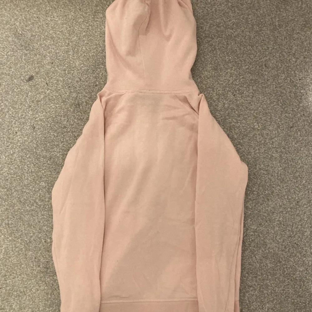 En ljusrosa GAP zip upp hoodie med bruna bokstäver, köpt secondhand men har själv aldrig använt den. Varan är i bra skick och ser knappt använd ut. Skriv gärna vid funderingar!!!. Hoodies.